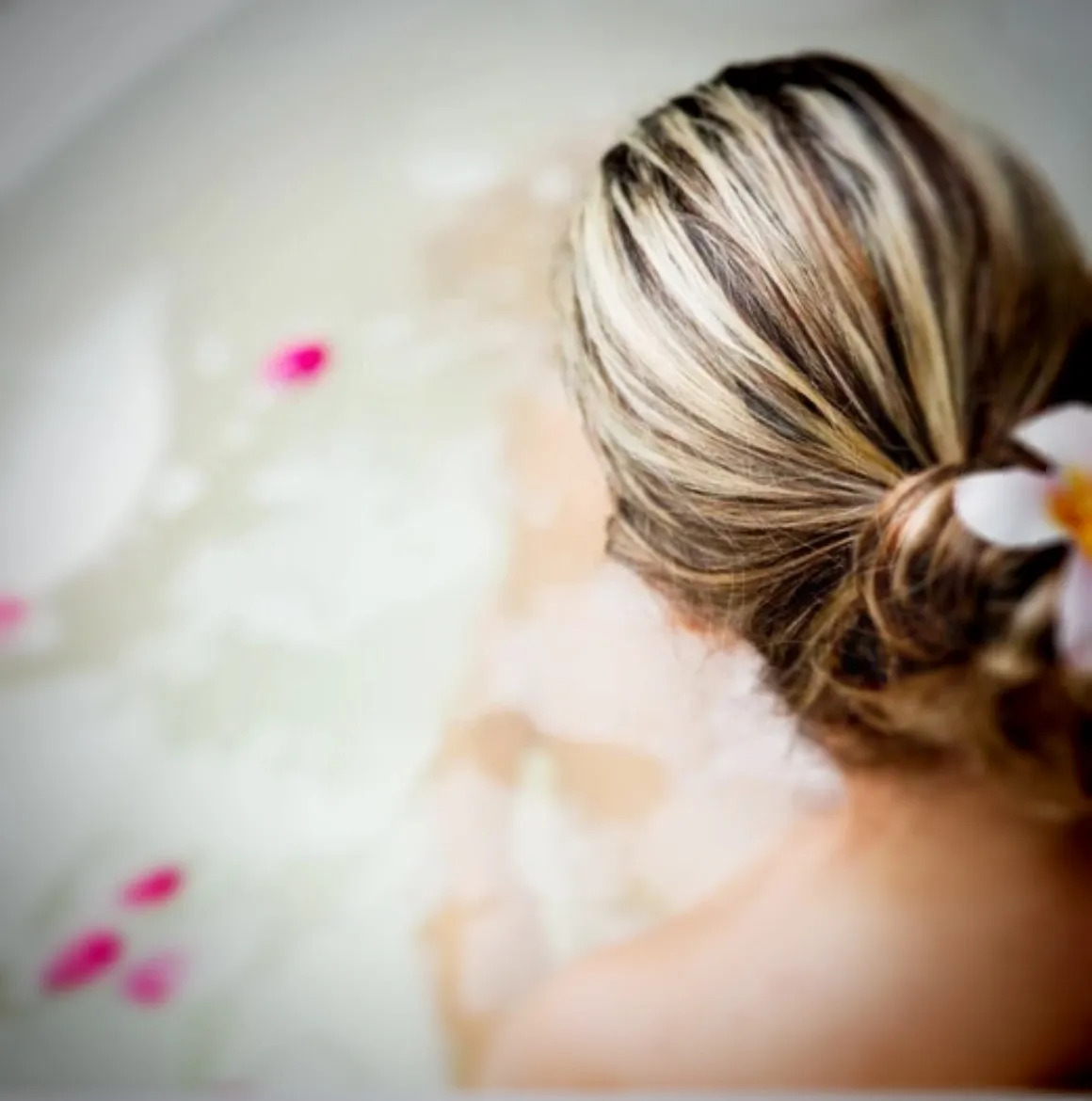 Woman relaxing in flower petal bath as a part of faith filled self care