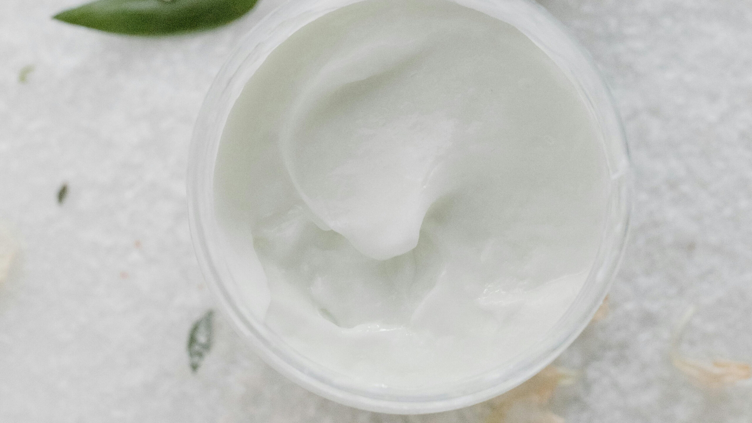 open jar of whipped tallow body butter with green leaf - Everlasting Organics grass fed tallow skincare