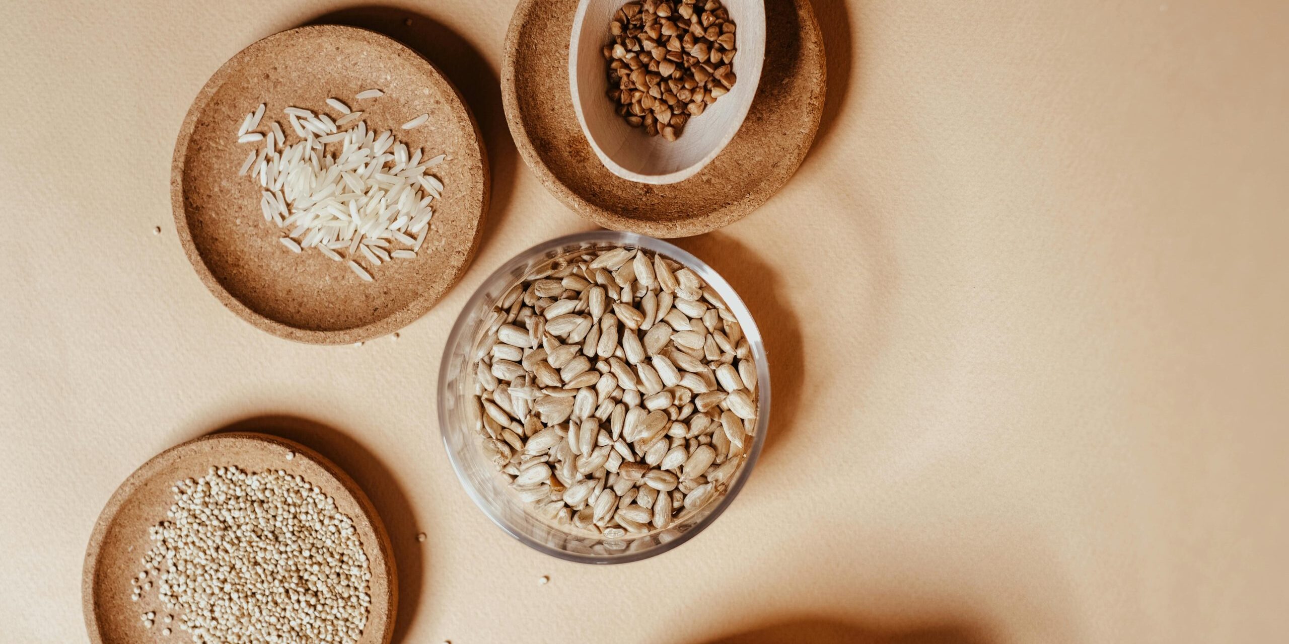 Assorted seeds and grains in wooden bowls including sunflower seeds, sesame, and flaxseed representing the Seeds & Grains ingredient library at Everlasting Organics