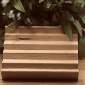Top view of Adler elevated ridged wood soap dish on bamboo surface with green plants showing deep drainage channel design