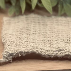 Natural sisal soap saver bag with wooden bead drawstring on bamboo surface